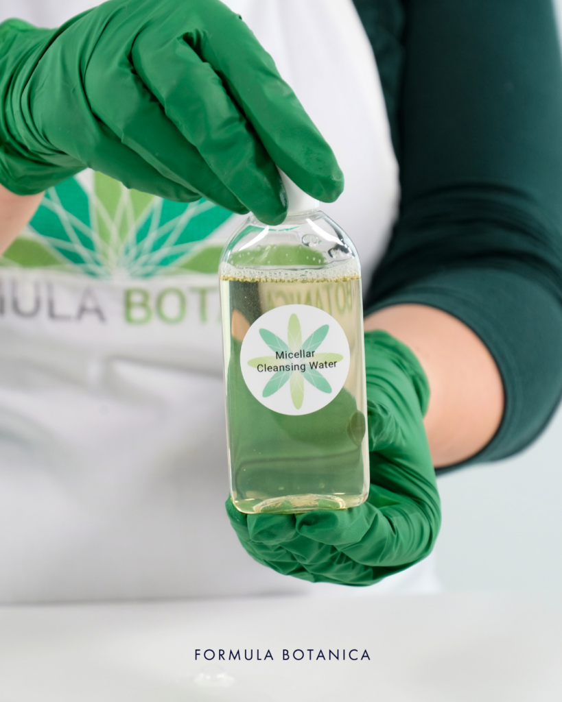 gloved hands holding a bottle of micellar water